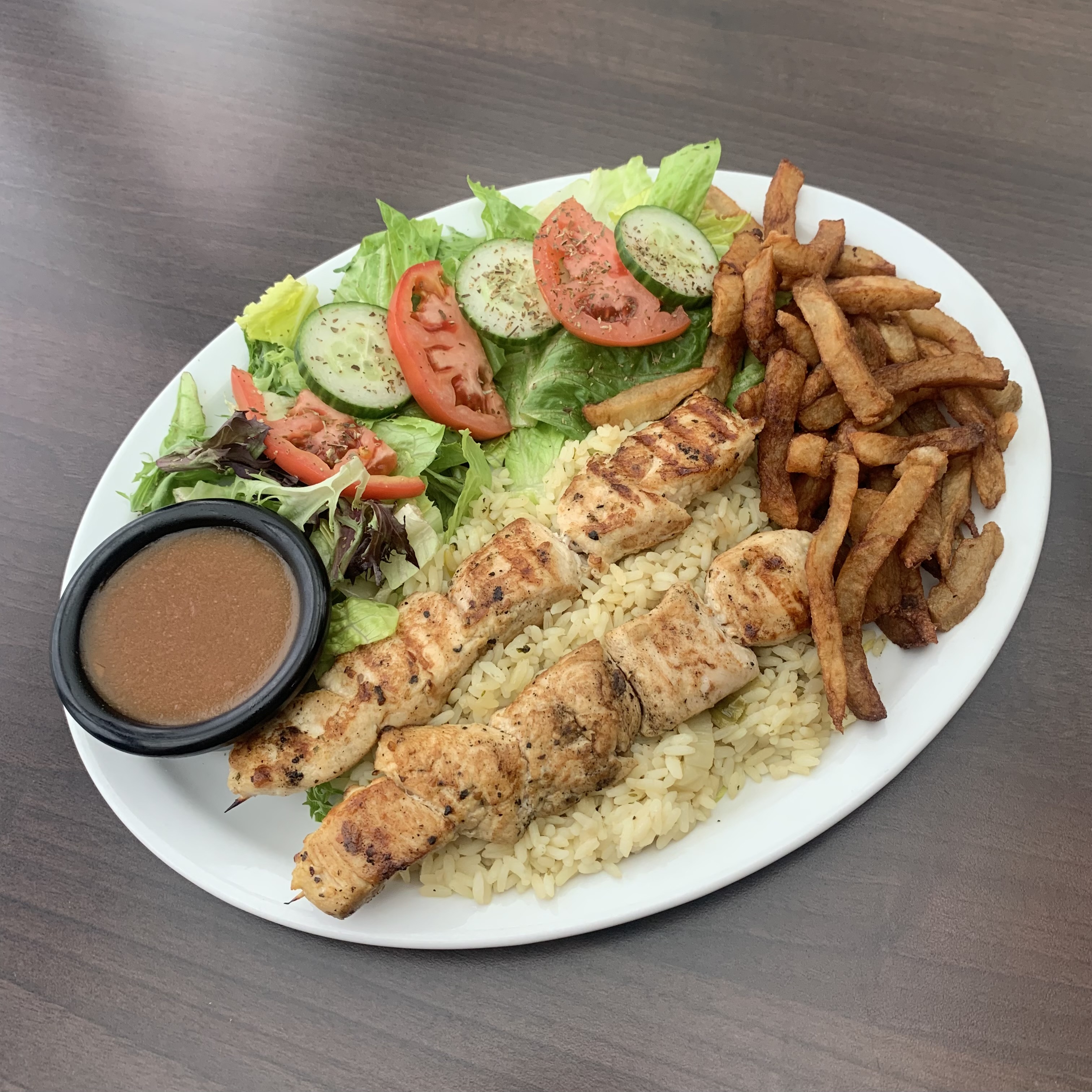 Brochettes de poulet avec riz, frites et salade